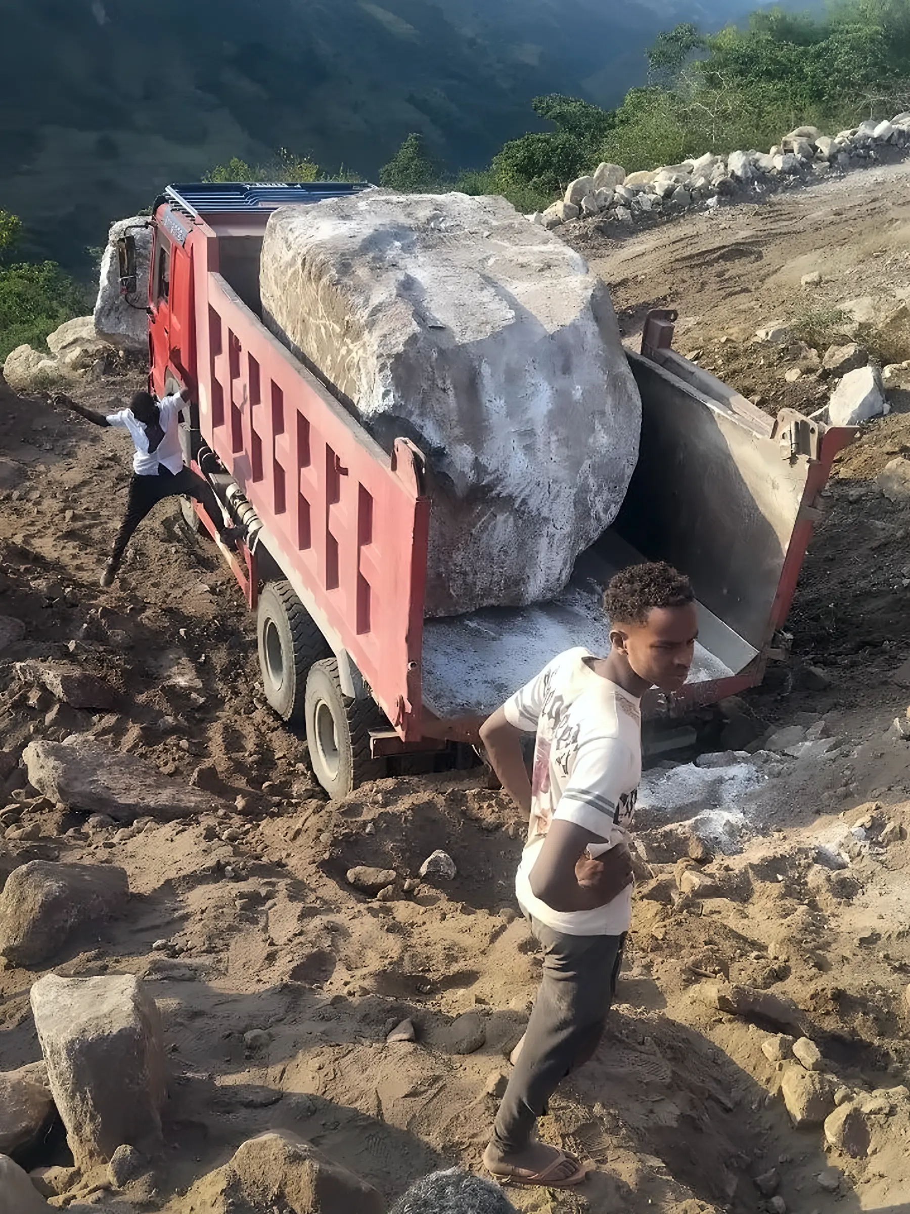ከባድ የጭነት መኪና ትልቅ ጥሬ ዕንጩን በቁፋሮ መንገድ ላይ ሲያጓጉዝ
